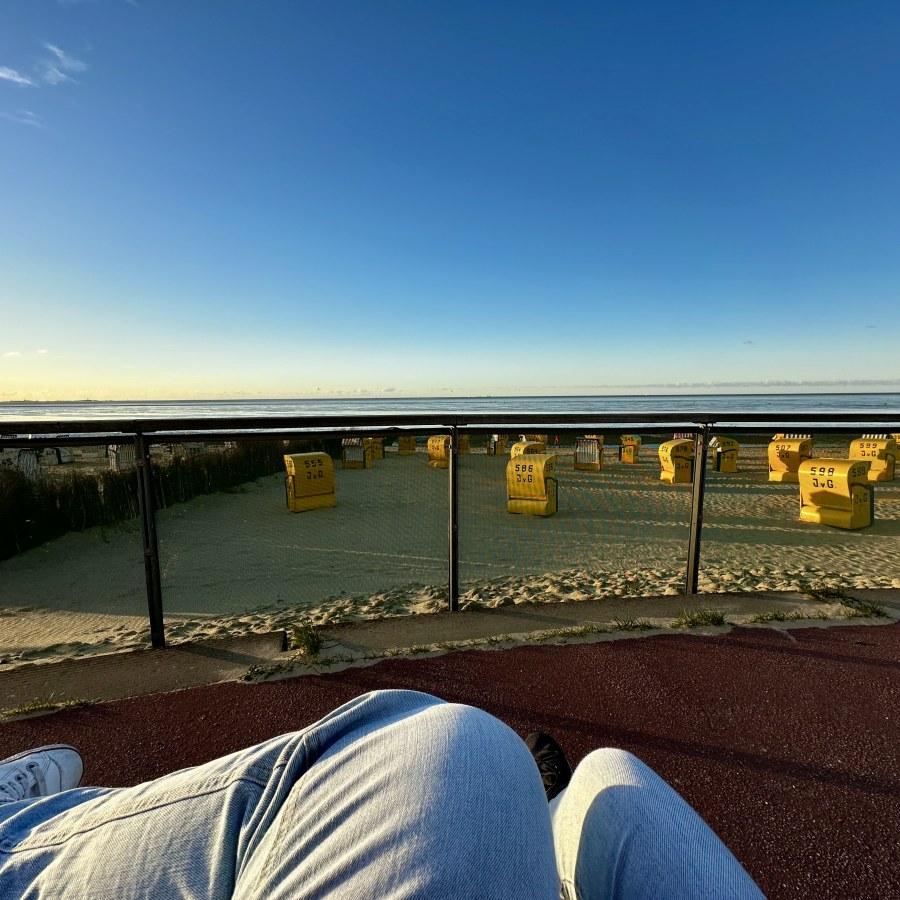 Entspannende Bankpause an der Strandpromenade mit Blick auf die Nordsee und Strandkörbe.